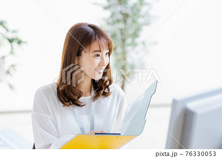明るい室内でデスクワーク中の女性 76330053
