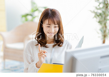 明るい室内でデスクワーク中の女性 76330054