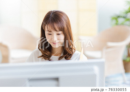 明るい室内でデスクワーク中の女性 76330055
