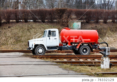Sewage truck on pumping feces with a bright red cistern. 76332129