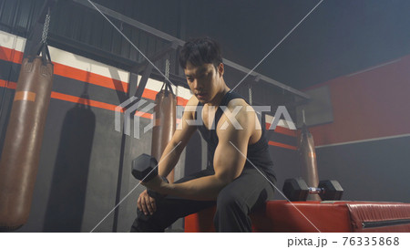 Portrait of strong Asian man lifting dumbbells, doing exercise, working out, and training in boxing gym or fitness center in sport club. Recreation concept. Lifestyle activity people. Portrait of strong Asian man lifting dumbbells, doing exercise, working out, and training in boxing gym or fitness center in sport club. Recreation concept. Lifestyle activity people. 76335868