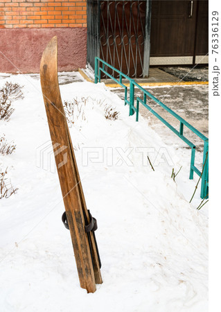wooden skis in snowdrift near entrance to house 76336129