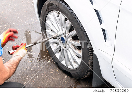 technician unscrews car wheel by lug wrench technician unscrews car wheel by lug wrench 76336269