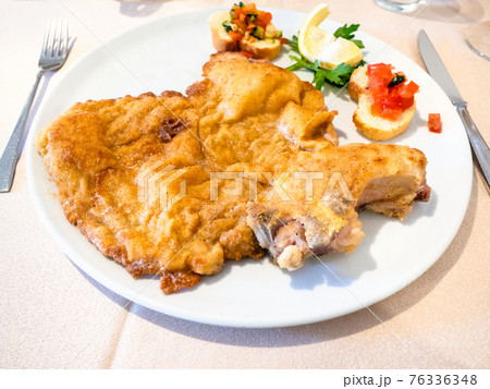 Italian cuisine - Cotoletta alla Milanese on plate 76336348