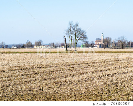 rural landscape with harvested fileld and village 76336507