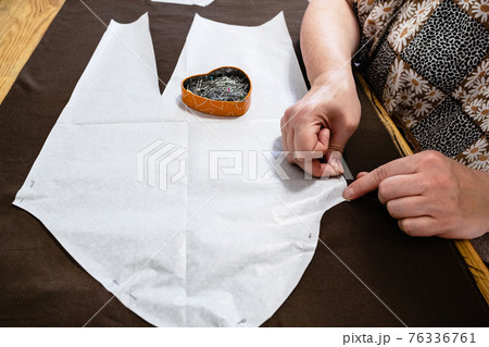 tailor fixes paper pattern layout to brown fabric tailor fixes paper pattern layout to brown fabric 76336761