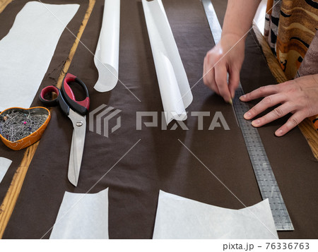woman draws pattern on brown fabric with rule woman draws pattern on brown fabric with rule 76336763