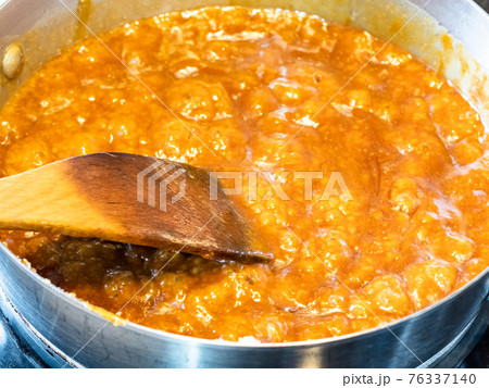 cooking salted butter caramel sauce at home kitchen - boiling melted sugar and butter and cream in steel pan close up 76337140
