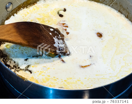 cooking salted butter caramel sauce at home kitchen - mixture of melted sugar and butter with added cream in steel pan close up 76337141