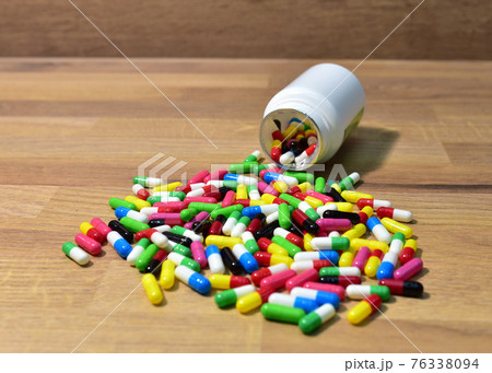 Pills from a plastic bottle on wooden background.  76338094