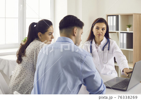 Medical doctor showing diagnosis results to patients on laptop screen in office 76338269