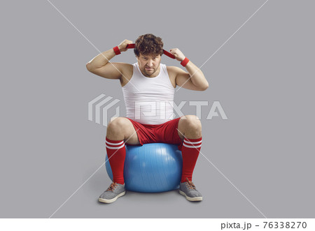 Funny angry chubby man sitting on fitness ball and getting ready for gym workout Funny angry chubby man sitting on fitness ball and getting ready for gym workout 76338270