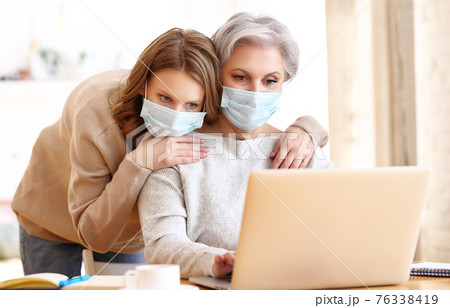 Young daughter with aged mother browsing laptop at home during COVID 19 76338419