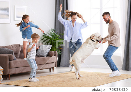 Cheerful family with kids and dog dancing at home 76338439