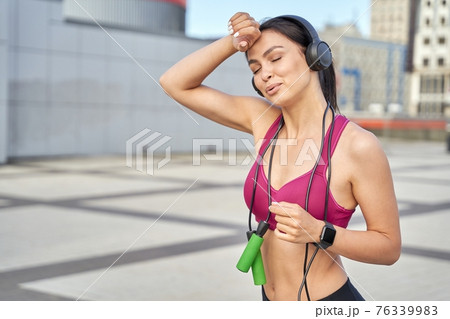 Sporty young woman with wireless headphones in training Sporty young woman with wireless headphones in training 76339983