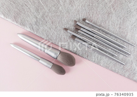 Silver color makeup brushes on pink and gray background Silver color makeup brushes on pink and gray background 76340935