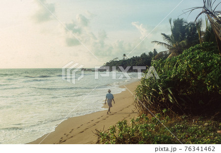 A traditonally dressed man walks by the sea at Negombo beach in Sri Lanka. Retro 1993 film capture. 76341462