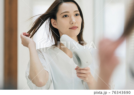 洗面所でドライヤーを使う若い女性 76343690