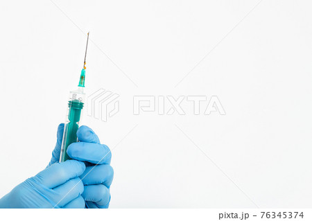 A doctor's hand in a medical glove holds a syringe with a needle to protect against the flu virus A doctor's hand in a medical glove holds a syringe with a needle to protect against the flu virus 76345374