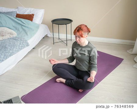 Girl meditate at home in bedroom near bed. Online Girl meditate at home in bedroom near bed. Online 76348569