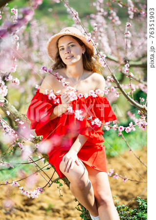Portrait of happy girl in red dress in blooming spring garden Portrait of happy girl in red dress in blooming spring garden 76351903