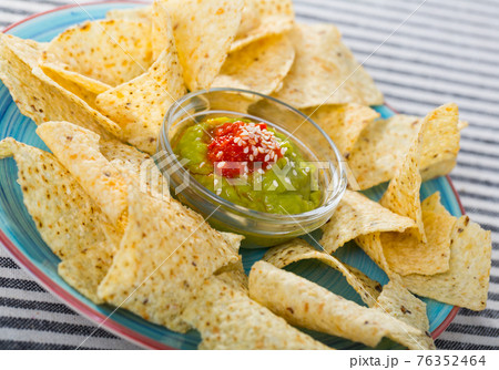 Corn chips nachos on plate with homemade guacamole sauce 76352464