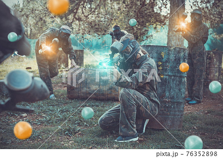 Team of adult people playing paintball on battlefield outdoor, r Team of adult people playing paintball on battlefield outdoor, r 76352898