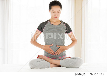 おなかを抑える女性 76354847