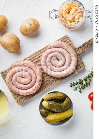 Wurst or Bratwurst with Fermented Cabbage, Pickled Cucumbers, and Spices, on white background, top view flat lay Wurst or Bratwurst with Fermented Cabbage, Pickled Cucumbers, and Spices, on white background, top view flat lay 76358145