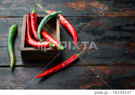Red and green chili pepper, in wooden box, on dark wooden background , with copyspace and space for text Red and green chili pepper, in wooden box, on dark wooden background , with copyspace and space for text 76358147