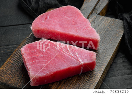 Raw tuna steak, on wooden cutting board, on black wooden background 76358219