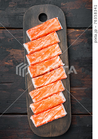 Fresh Crab meat stick surimi , on wooden cutting board, on dark wooden background Fresh Crab meat stick surimi , on wooden cutting board, on dark wooden background 76358341