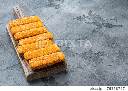 Frozen fish sticks. Organic fish food, on wooden cutting board, on gray background , with copyspace and space for text Frozen fish sticks. Organic fish food, on wooden cutting board, on gray background , with copyspace and space for text 76358747