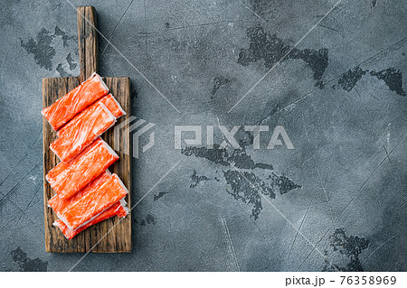 Asian snack surimi, on wooden cutting board, on gray background, top view flat lay , with copyspace and space for text Asian snack surimi, on wooden cutting board, on gray background, top view flat lay , with copyspace and space for text 76358969