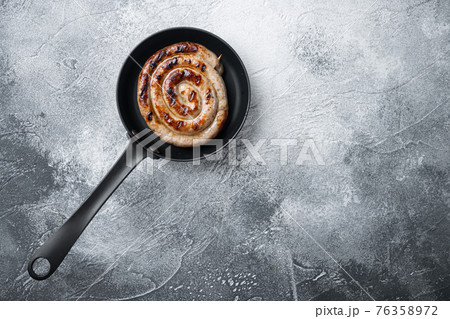 Grilled Spiral sausage in cast iron frying pan, on gray background, top view flat lay , with space for text copyspace Grilled Spiral sausage in cast iron frying pan, on gray background, top view flat lay , with space for text copyspace 76358972
