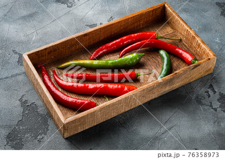 Ripe Red and green chili pepper, in wooden box, on gray background Ripe Red and green chili pepper, in wooden box, on gray background 76358973