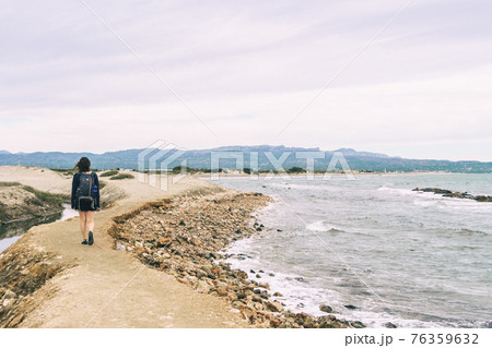girl strolling on the shore of the beach on a cloudy day girl strolling on the shore of the beach on a cloudy day 76359632