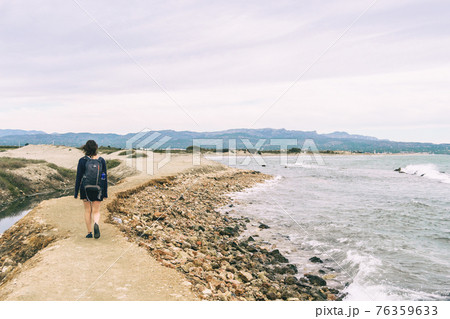 girl strolling on the shore of the beach on a cloudy day girl strolling on the shore of the beach on a cloudy day 76359633