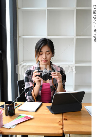 Portrait of female photographer checking pictures previews on camera. Portrait of female photographer checking pictures previews on camera. 76359931