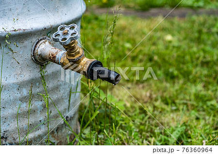 Old rusty rain barrel with water tap closeup Old rusty rain barrel with water tap closeup 76360964