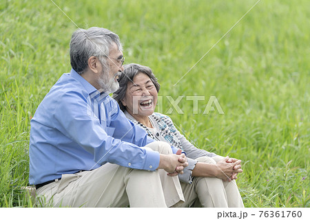屋外で座り会話するシニア夫婦 76361760