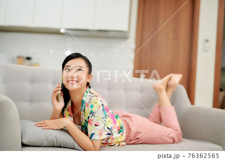 Pleasant talk with friend. Attractive smiling young redhead woman talking on cell phone while sitting on the beige sofa at home 76362565