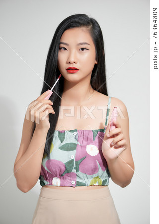 Attractive and beautiful Asian girl paint lips a pink lipstick, smiling make-up girl isolated on white background 76364809