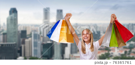 Shopping woman holding shopping bags above her head smiling during sale shopping over city background Shopping woman holding shopping bags above her head smiling during sale shopping over city background 76365761