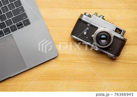 Workspace with laptop computer and camera on wooden table. Top view 76366945