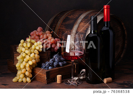 Wine bottles, grapes, glass of red wine and old barrel 76368538