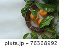 Clementines tangerines, twig with green leaves as spring decor and handmade  wreath from twig on gray paper background. 76368992