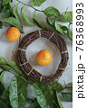 Clementines tangerines, twig with green leaves as spring decor and handmade  wreath from twig on gray paper 76368993