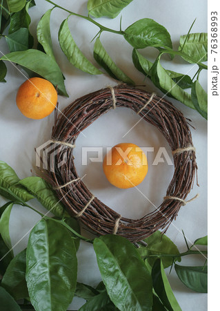 Clementines tangerines, twig with green leaves as spring decor and handmade  wreath from twig on gray paper 76368993