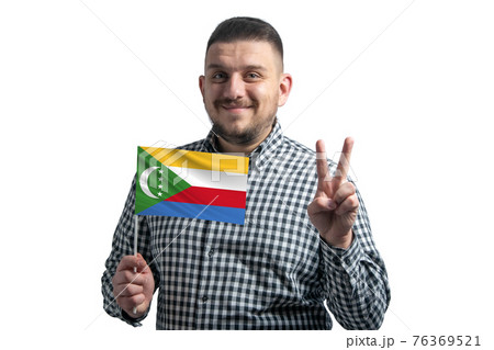 White guy holding a flag of Comoros and shows two fingers isolated on a white background White guy holding a flag of Comoros and shows two fingers isolated on a white background 76369521